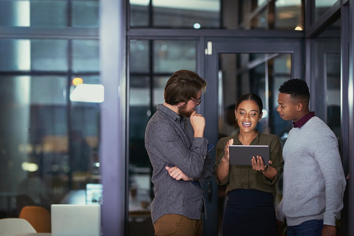 Shot of a group of young businesspeople using a digital tablet together during a late night at work